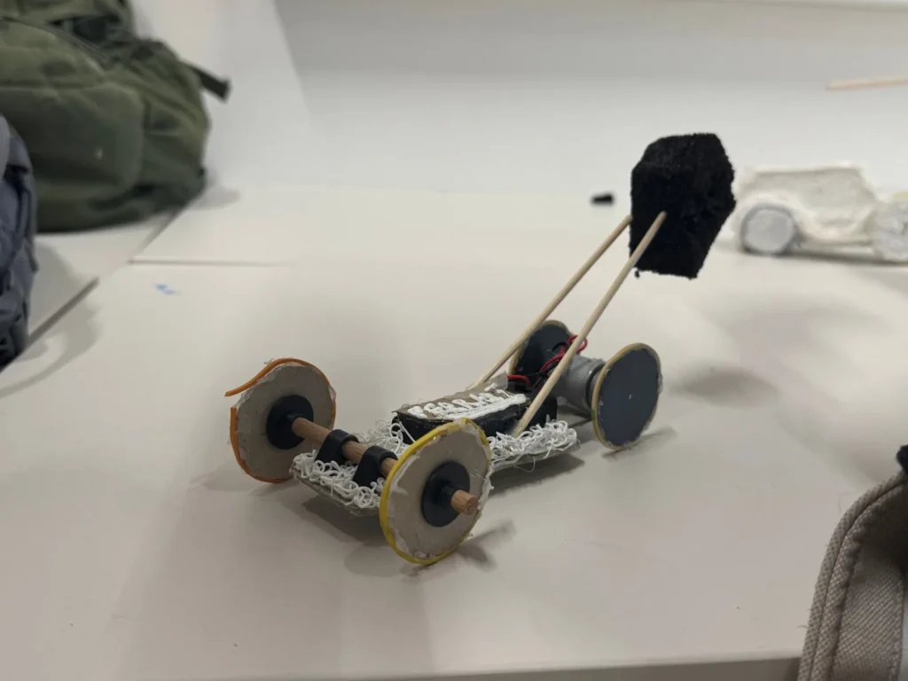 A car with a foam block mounted on bamboo sticks and cardboard wheels