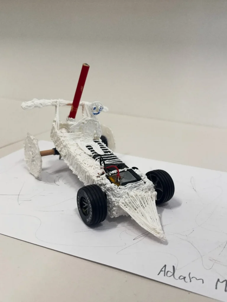 A car with a body built up with a 3D pen and a red pencil mounted as a mast