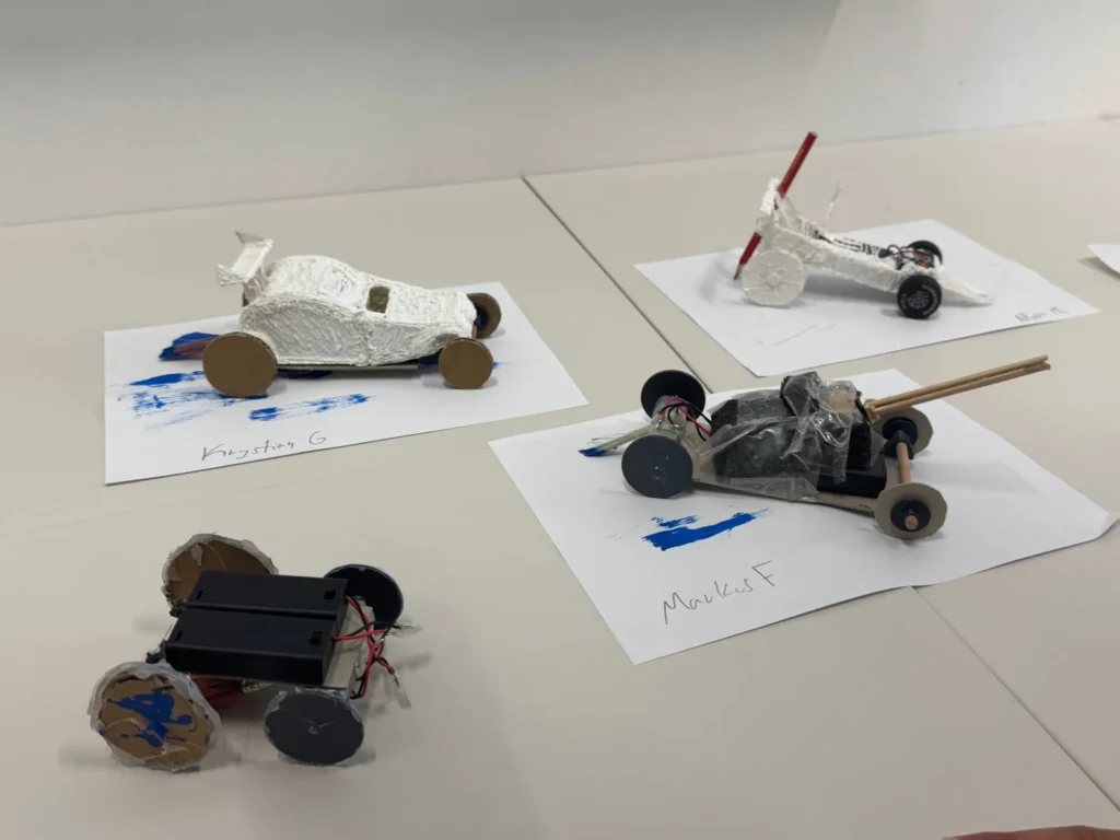 Four finished cars on sheets of paper