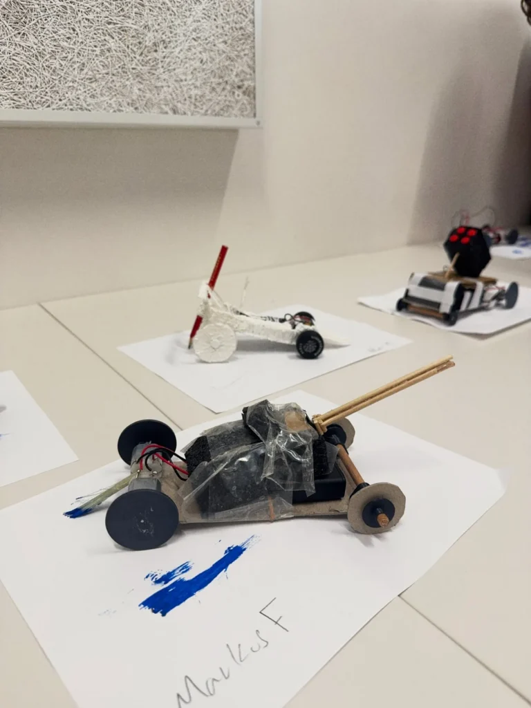 Finished cars standing on sheets of paper marked with the traces they drew