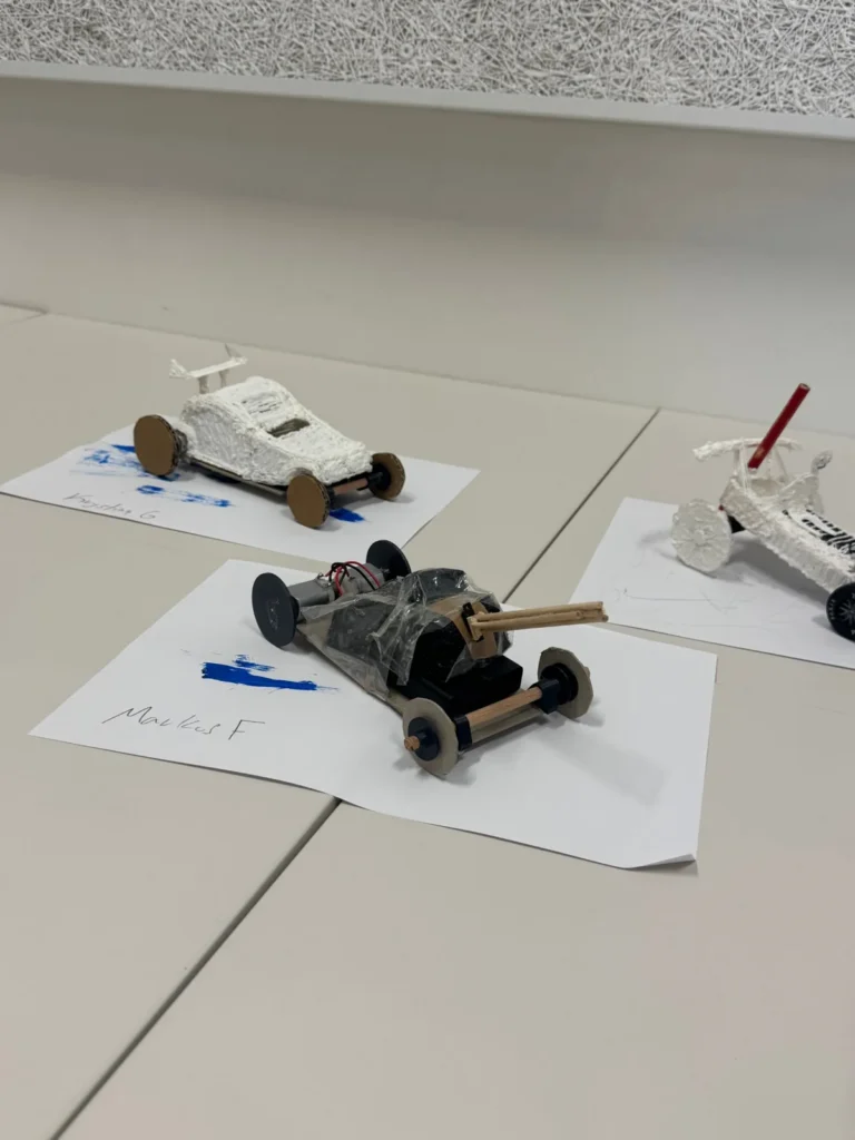 Two finished cars on their sheets of paper